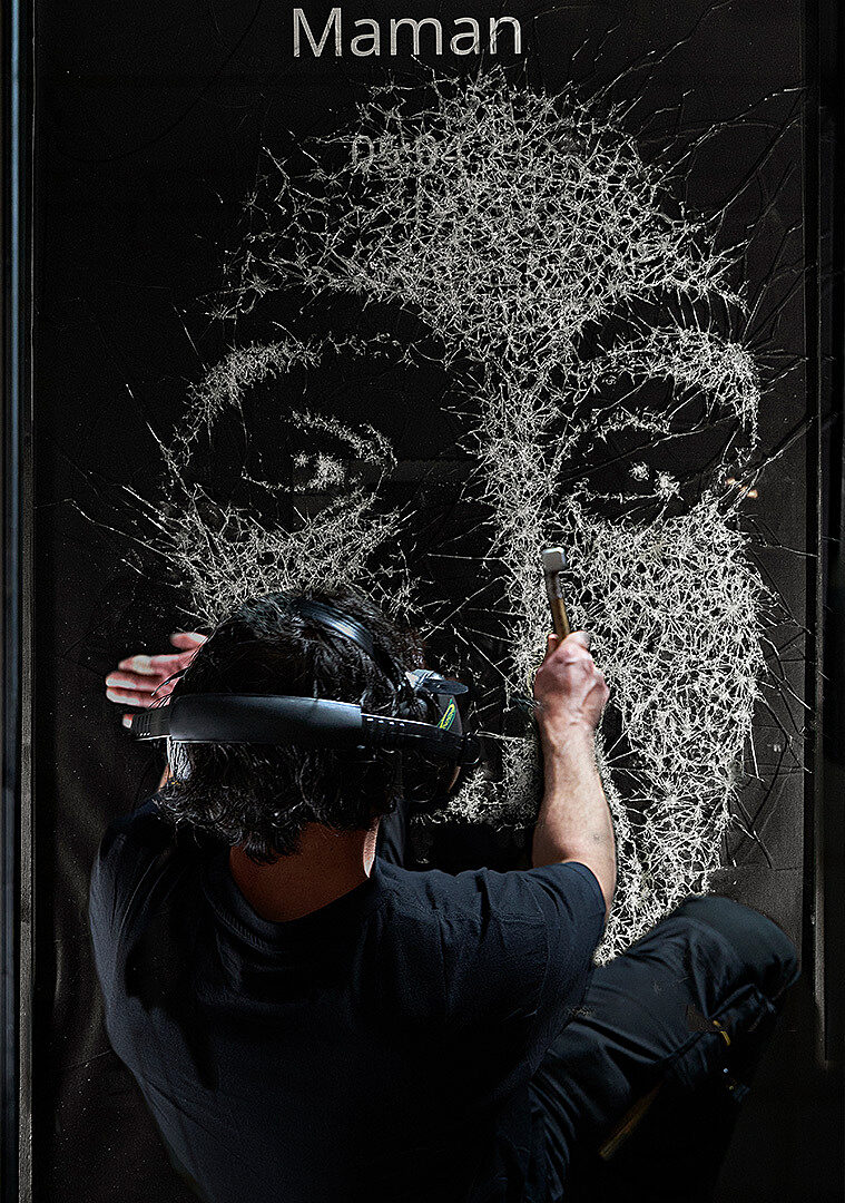 Artist Simon Berger etches the face of a victim into glass using a hammer.