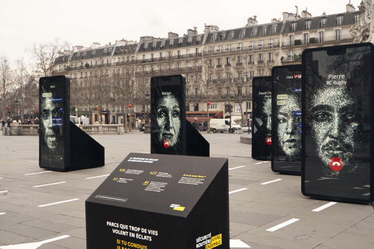Detail of the exhibition showing portraits and messages on large phone displays.
