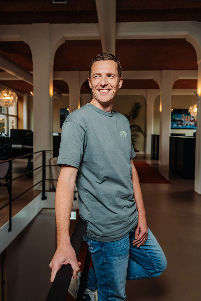 Portrait d’un collaborateur dans les bureaux de l’agence, souriant et détendu.