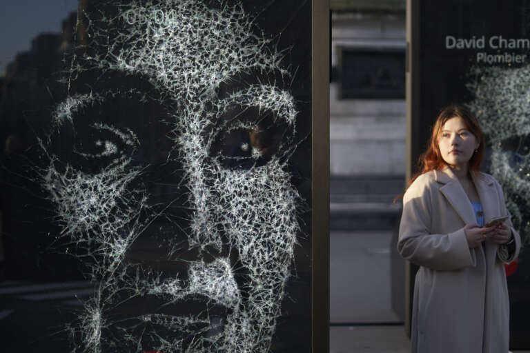Woman walking past a striking art display depicting a fractured face