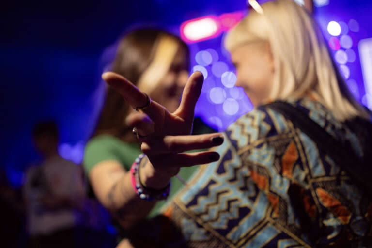 Two young women hugging on a party while pointing a finger to the camera